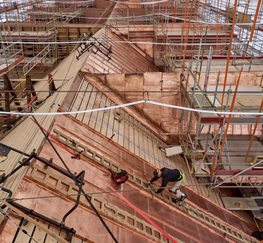 Des ouvriers de construction sur des échafaudages travaillent sur le toit d'un bâtiment