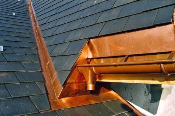 Gros plan sur un toit avec des gouttières en cuivre brillantes